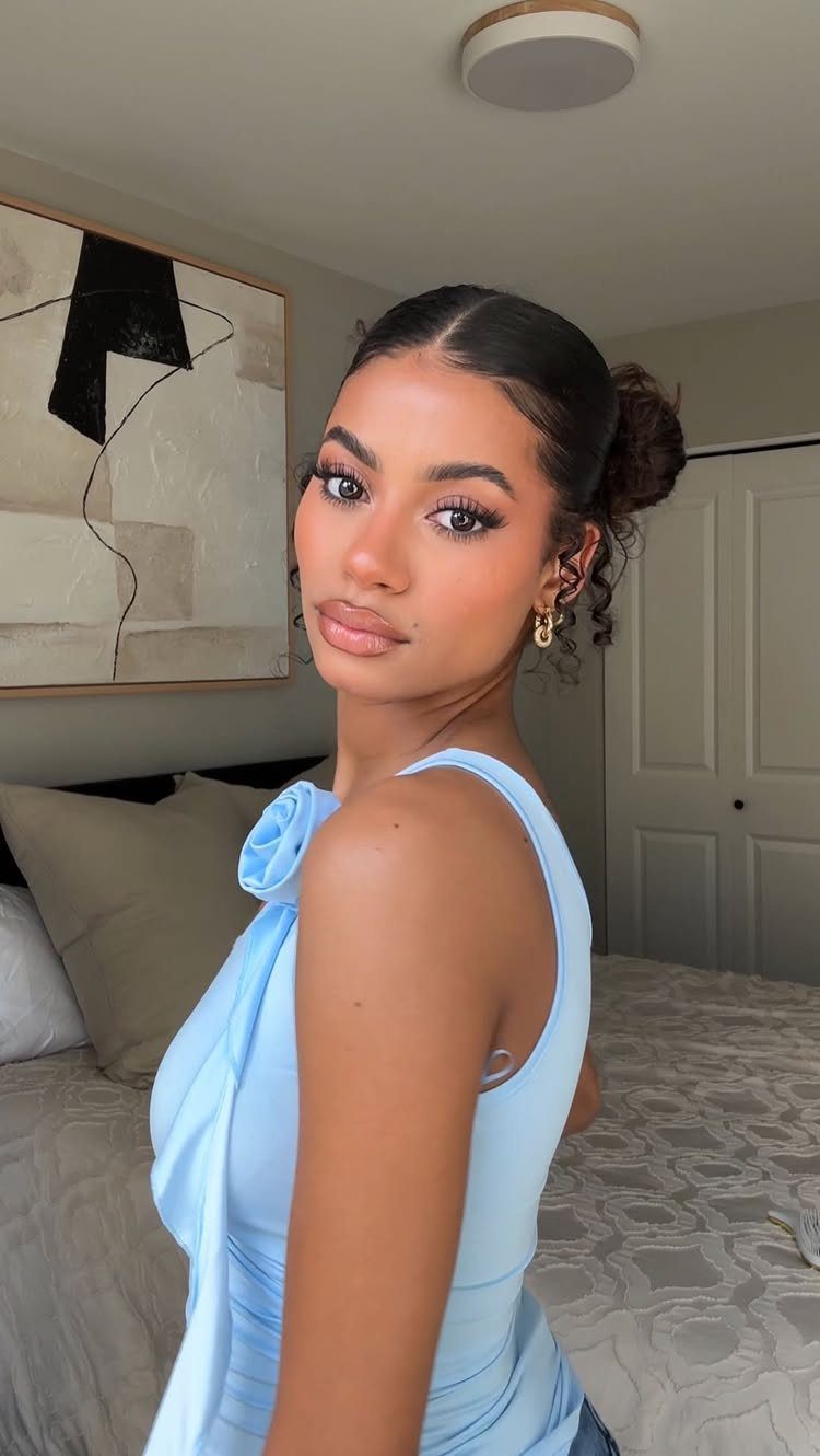 Woman posing with a neat, pulled-back bun and light blue top