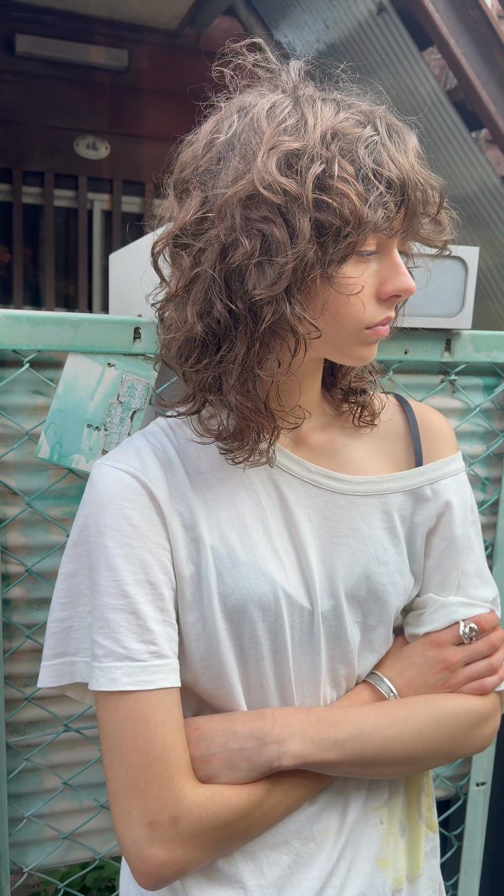Person showing a shaggy layered curly haircut with bangs