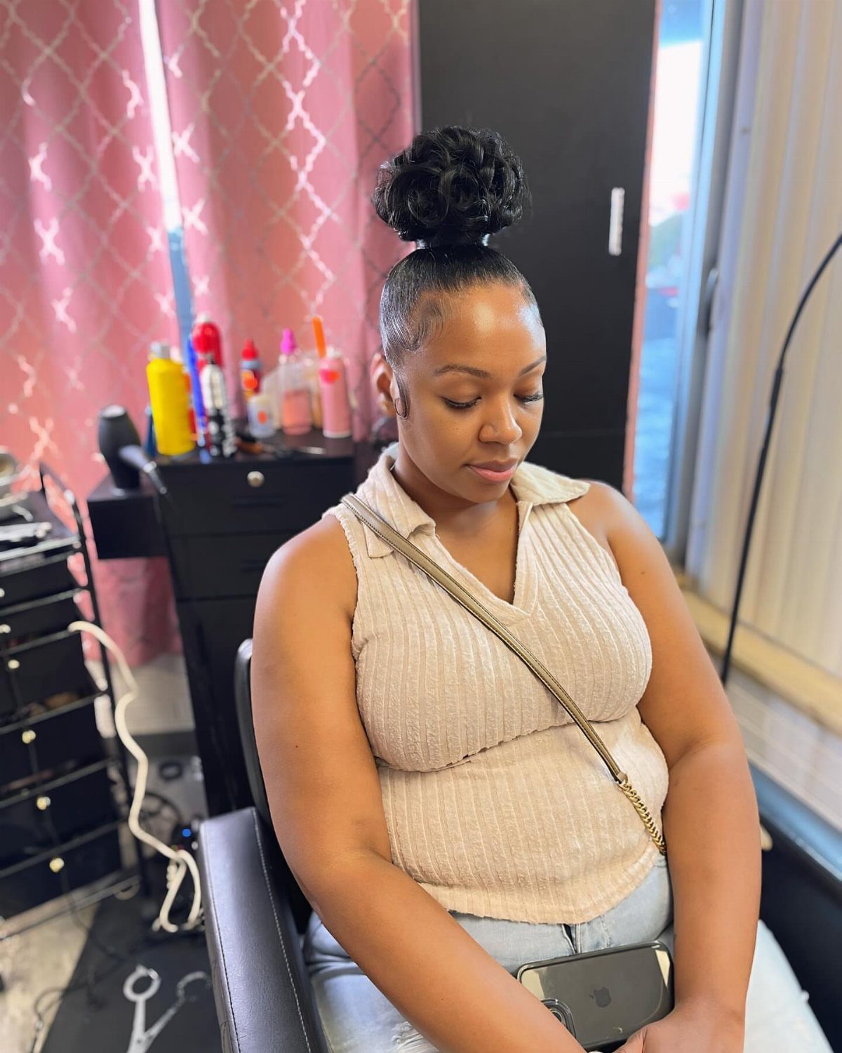 Woman wearing curly hair gathered into a high top knot in a salon