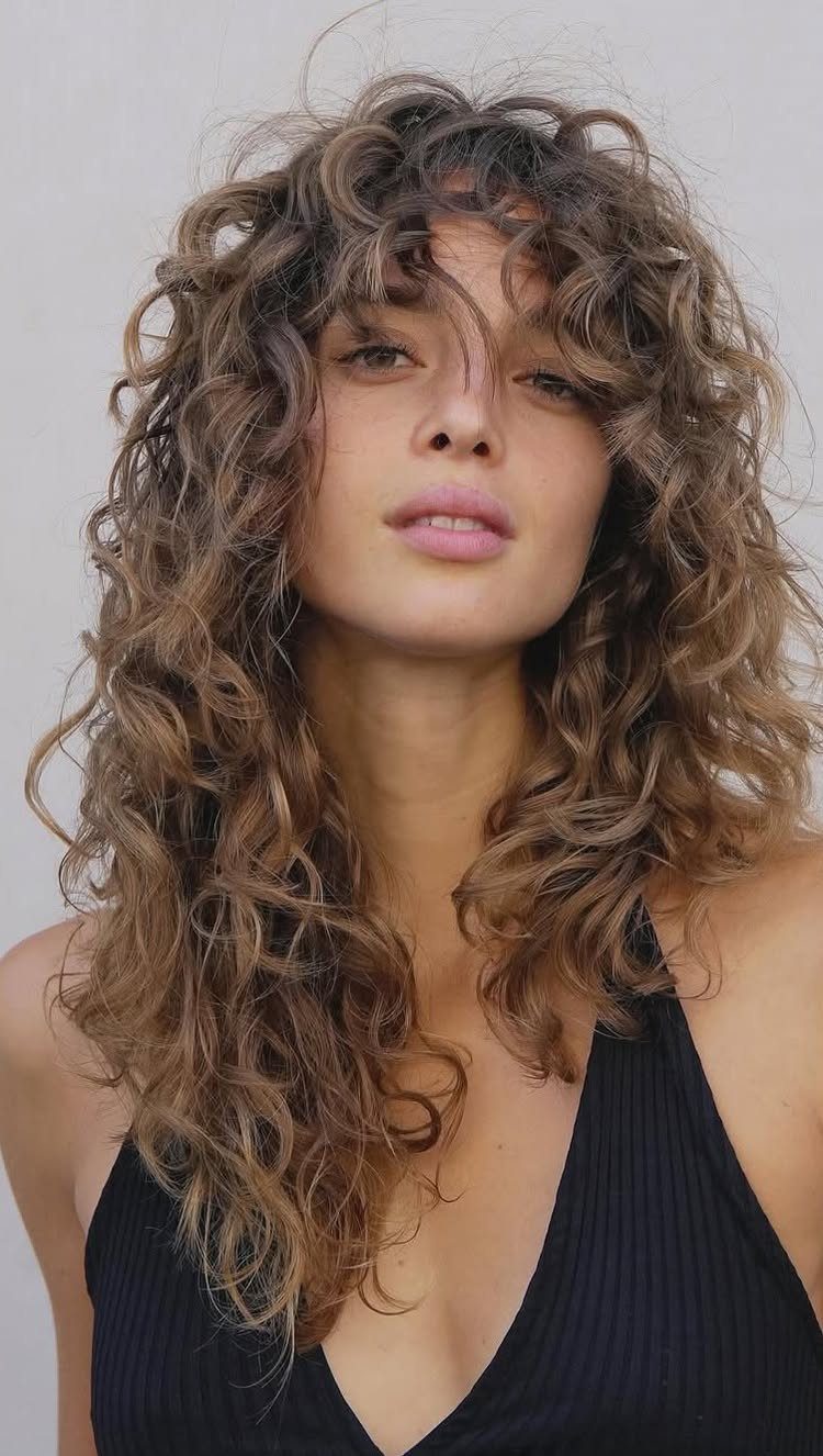 Woman showing a layered curly wolf cut with voluminous bangs