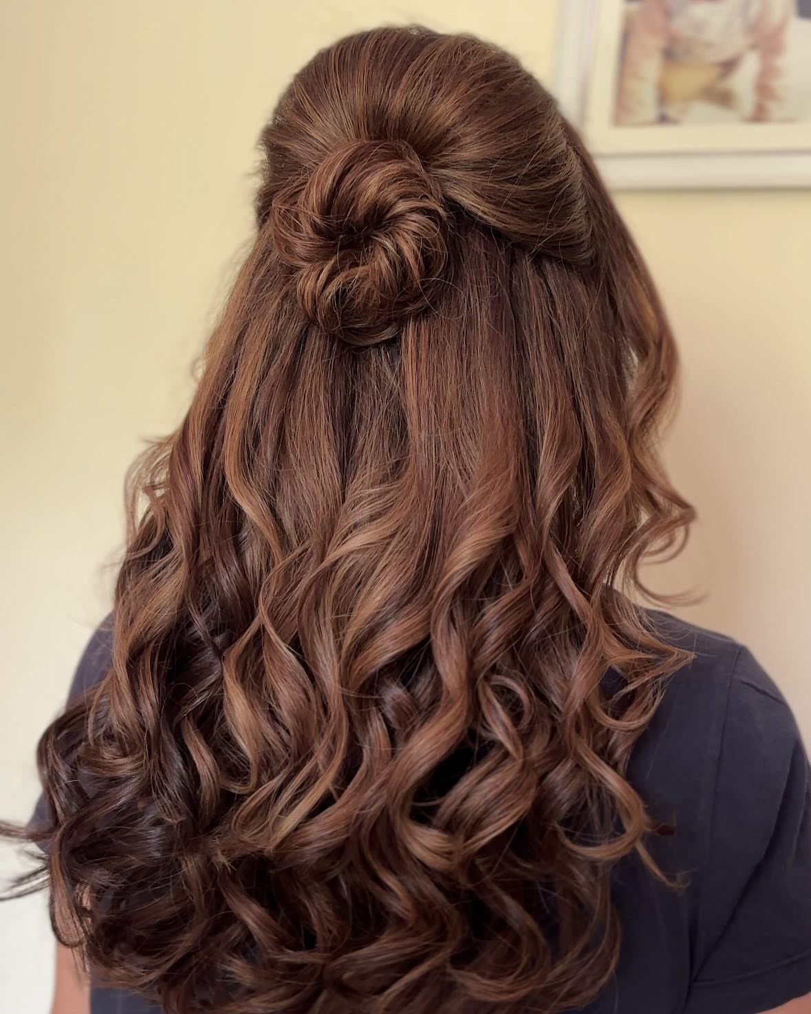 Long brown curls styled in a half-up bun with loose curls cascading down