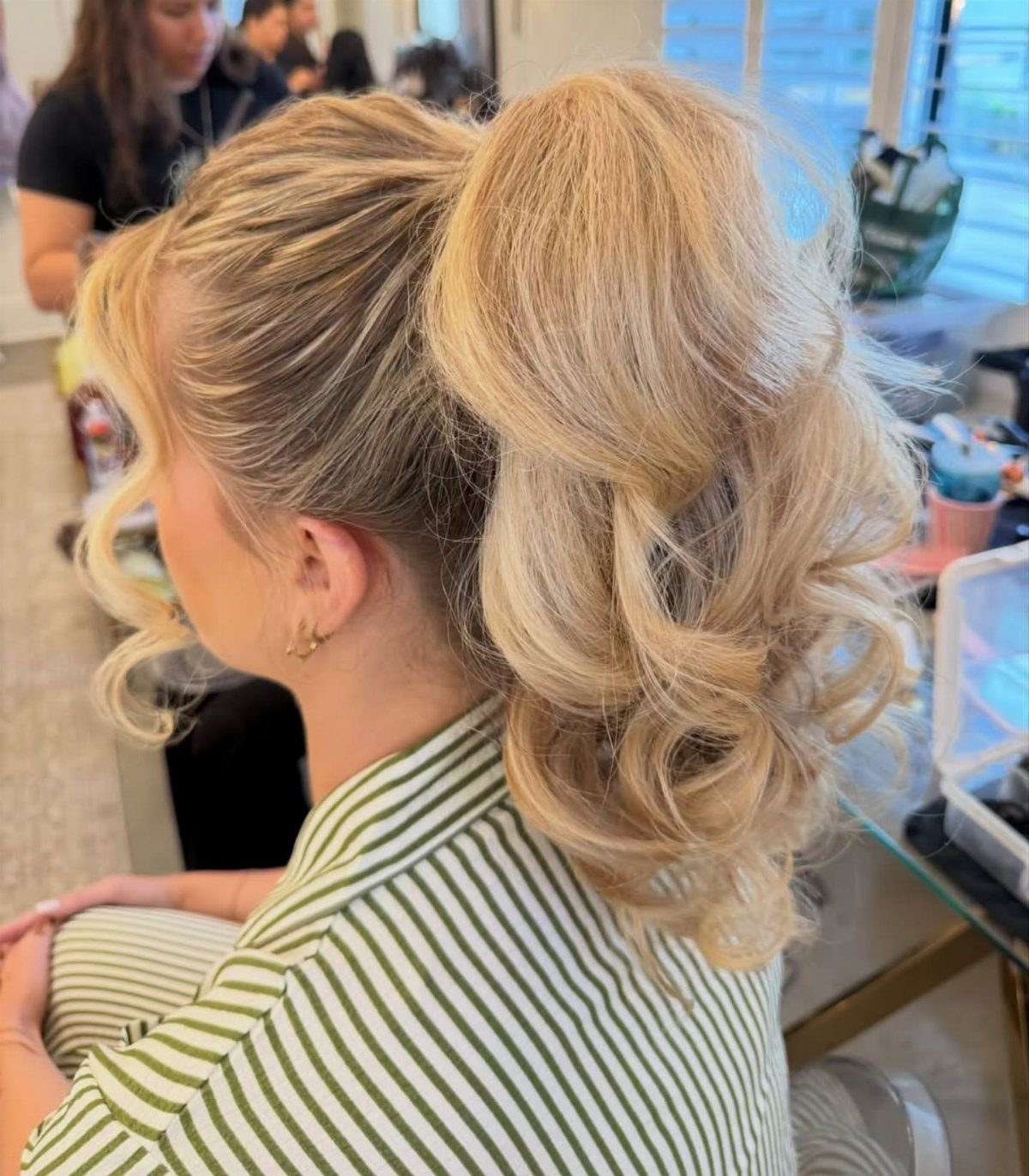 Blonde curls gathered into a high ponytail at a salon