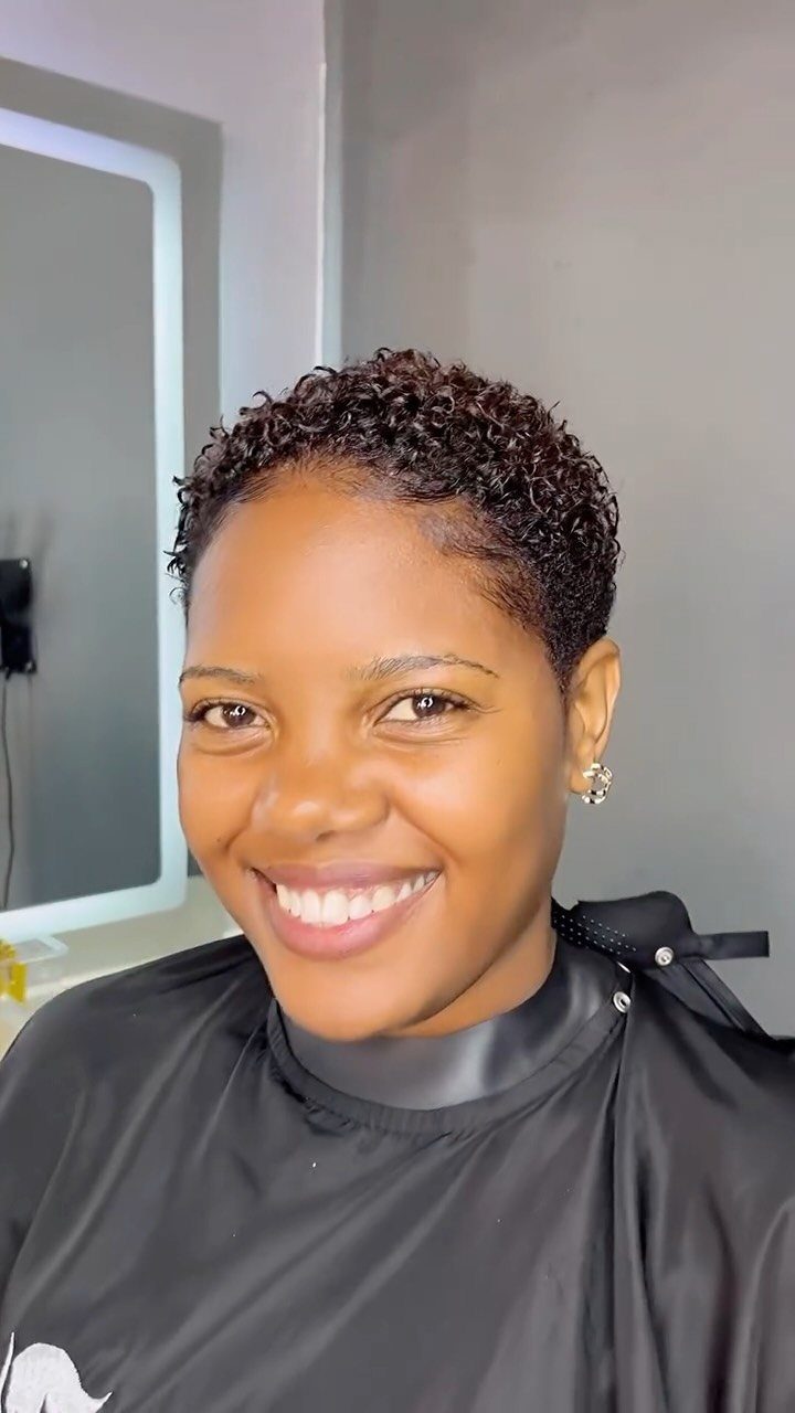 Woman smiling with a close-shaped curly pixie haircut and fuller curls on top
