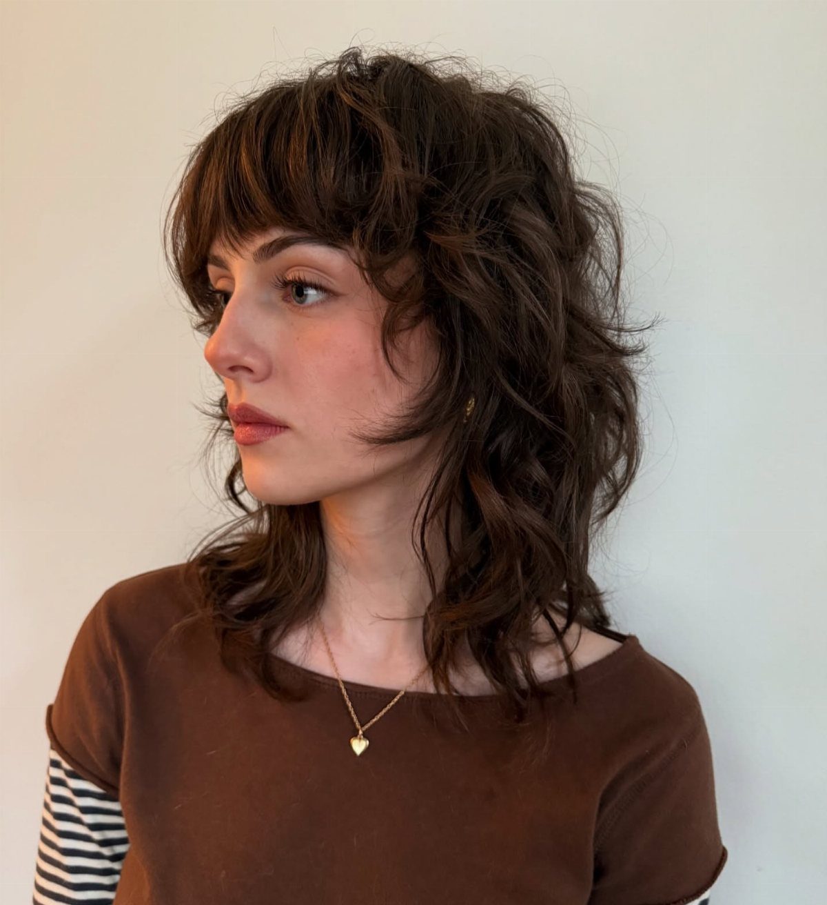 Woman wearing a layered curly shag with short bangs and face-framing waves
