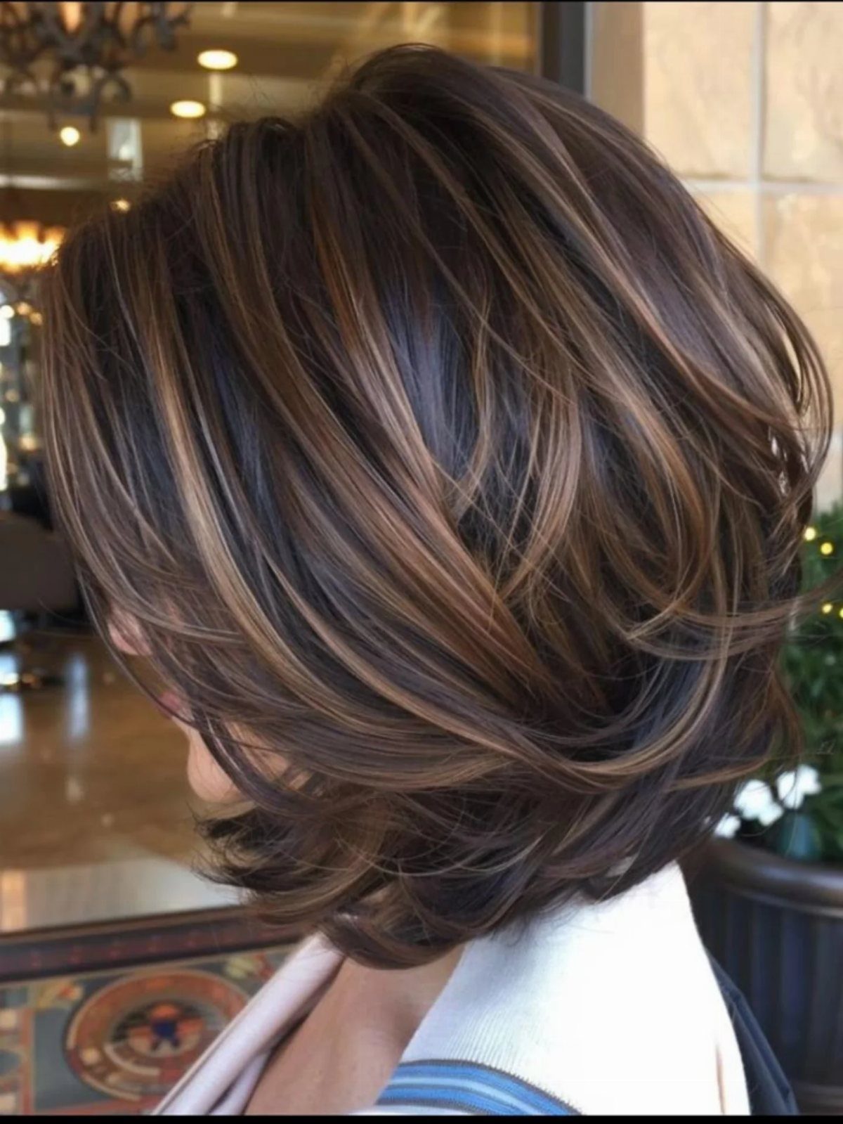 Layered wavy brown bob with highlighted strands styled in a rounded shape