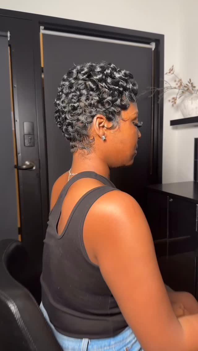 Short salt-and-pepper curls shaped close around the head, shown in profile