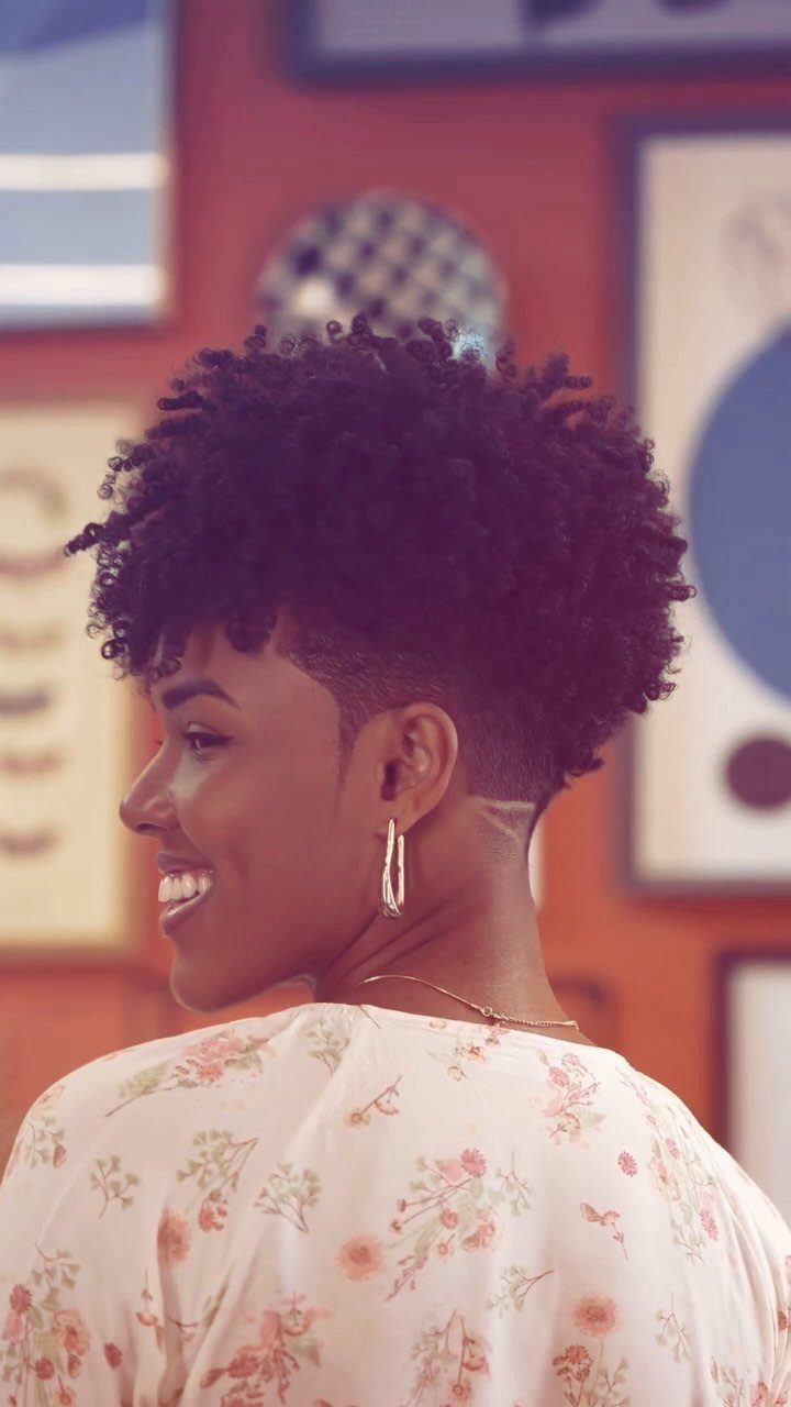 Woman with voluminous tapered curls, short sides and back, smiling in profile