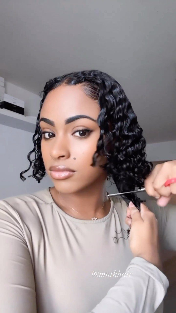 Woman with thick shoulder-length curls holding a section of her hair