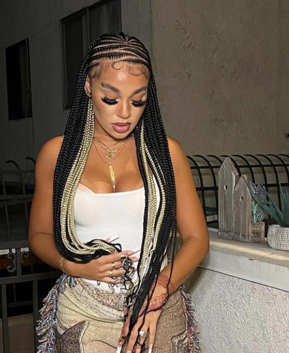 Woman wearing black braids with blonde face-framing money-piece sections