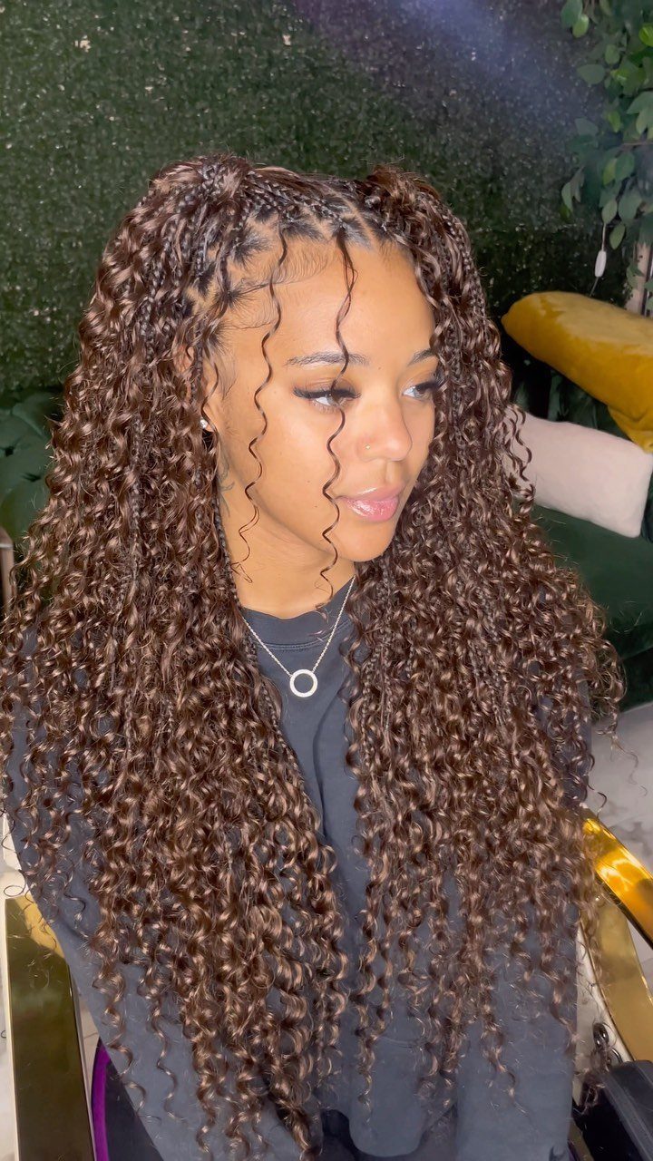 Woman wearing long caramel brown braids with curls and warm highlights