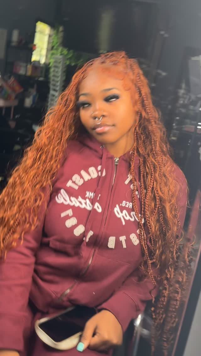 Woman wearing long, wavy copper-brown braids with a burgundy hoodie