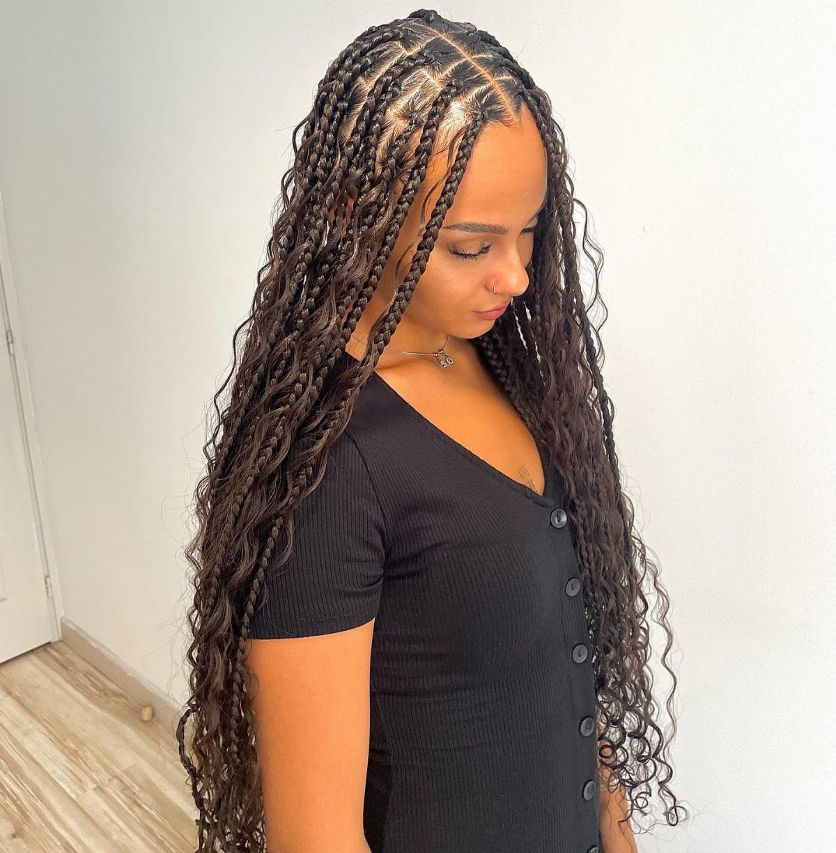 Woman displaying long curled goddess braids with loose dark waves