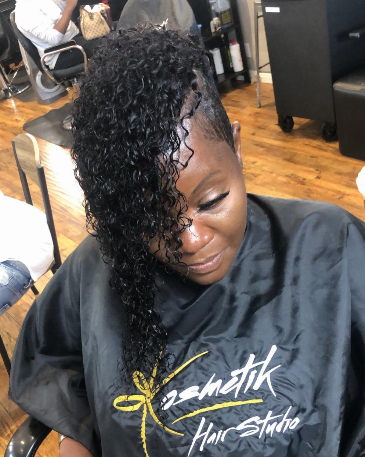 Woman with long curls swept over one side and a shaved side in a salon
