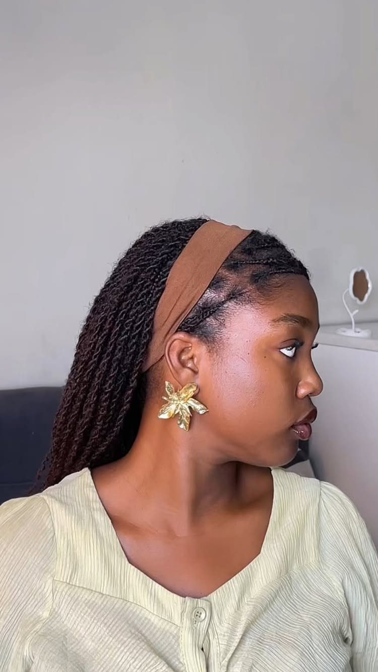 Woman wearing long dark twists swept back with a wide tan headband
