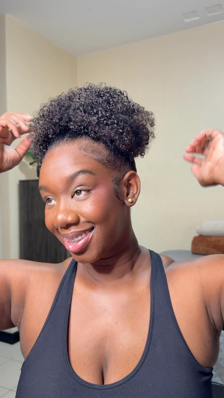 Woman posing with natural curls gathered into a high puff