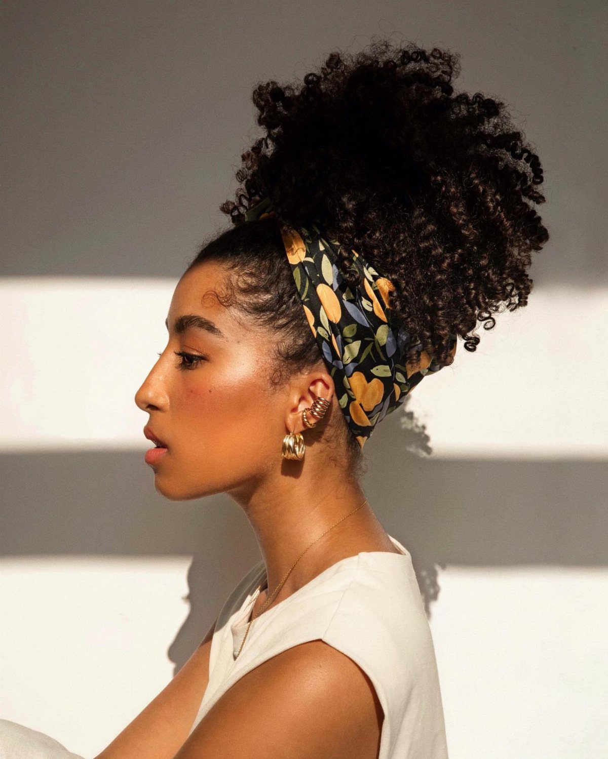 Woman wearing a natural curly pineapple puff with a patterned headscarf