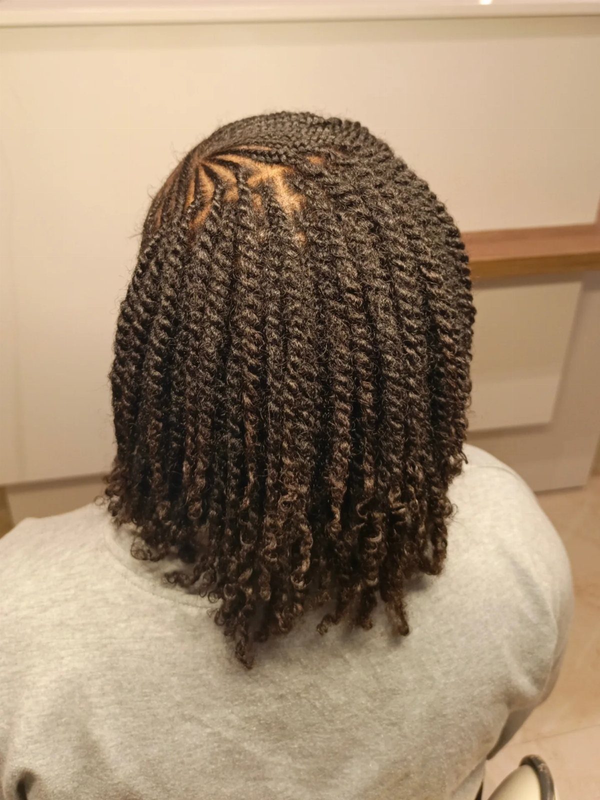 Dark shoulder-length mini twists cover the back of a person's head