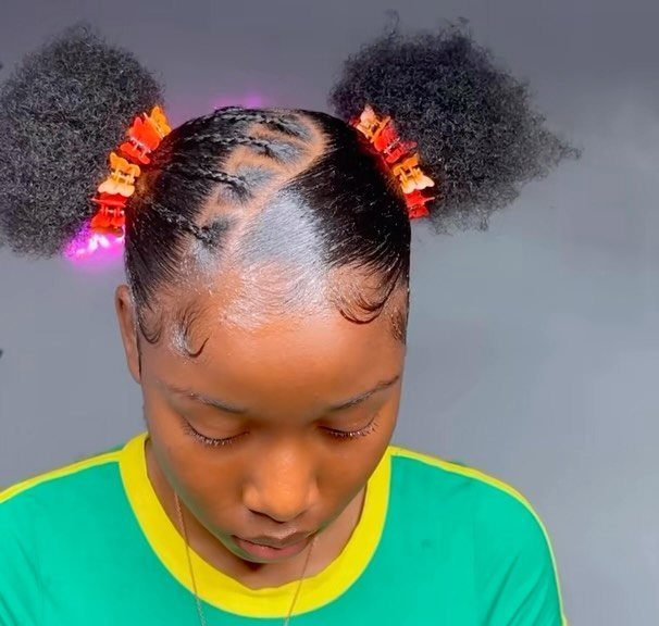Natural hair styled in two clipped high curly puffs with sleek parted sections
