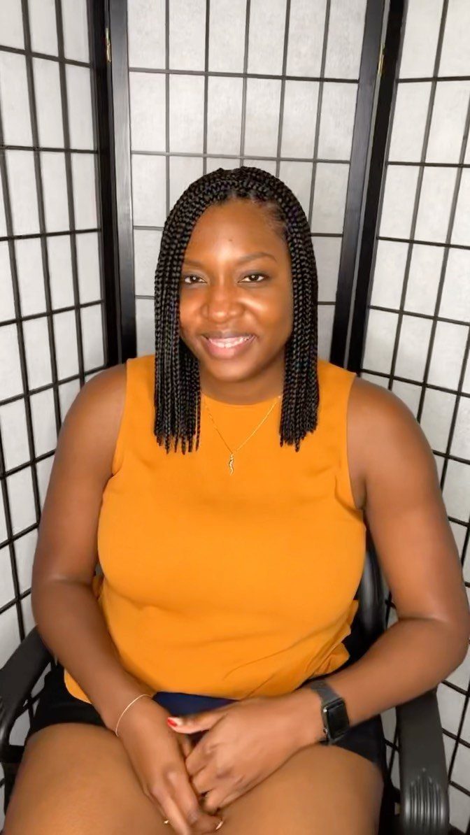 Woman wearing long, thin black box braids with a center part