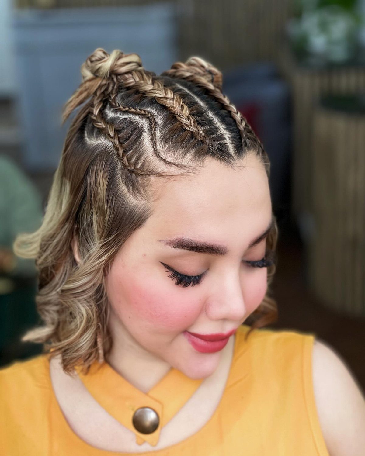 Woman wearing paired Dutch braids with small buns and loose curls