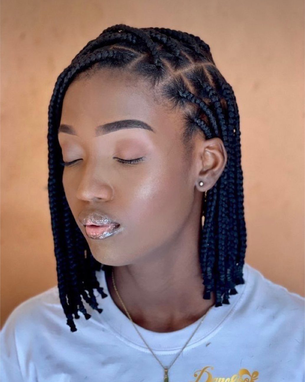 Short scalp-hugging braids curve into neat shoulder-length rows on a woman