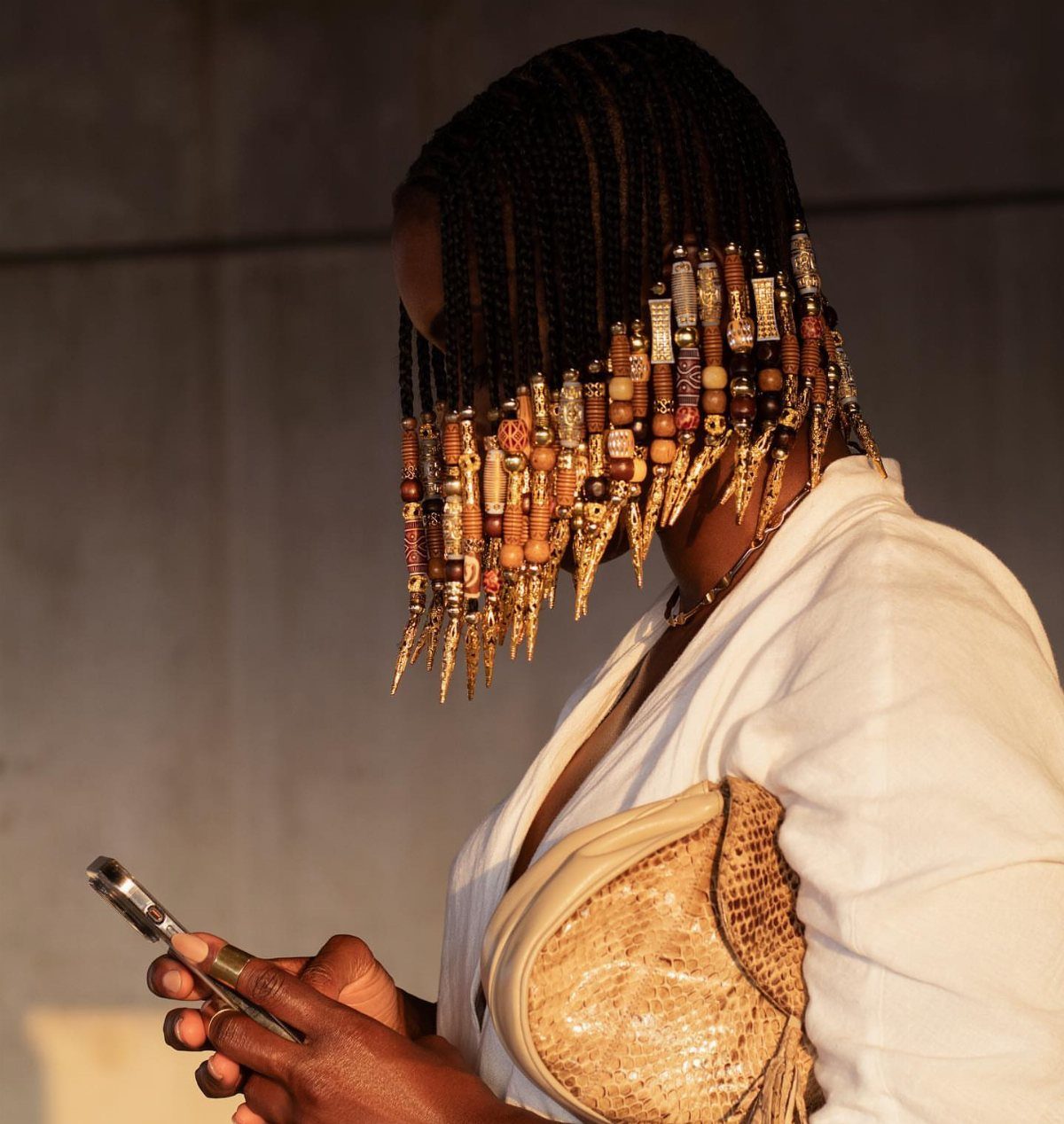 Short braids with wooden beads and gold ornaments hang over a person's face