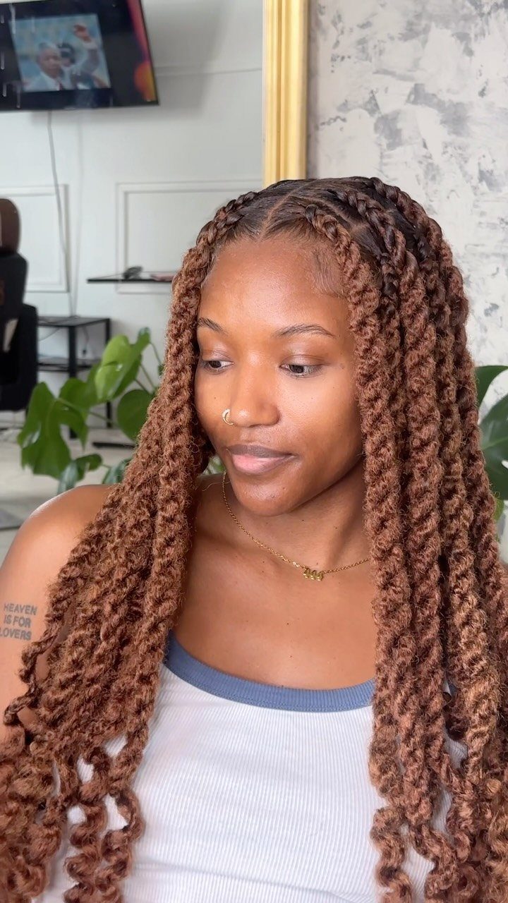 Long reddish-brown twists with loose curls frame a woman’s face