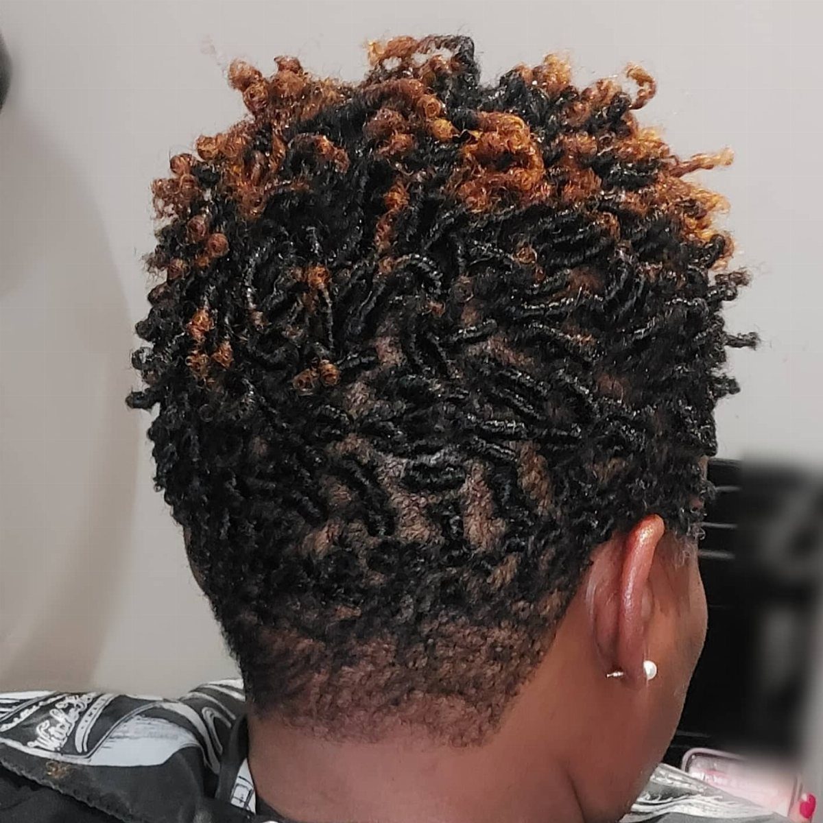Short natural hair styled in tight black twists with copper-brown tips
