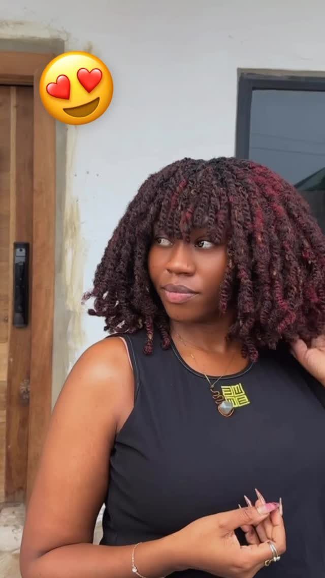 Woman wearing shoulder-length reddish twists with bangs and a black sleeveless top