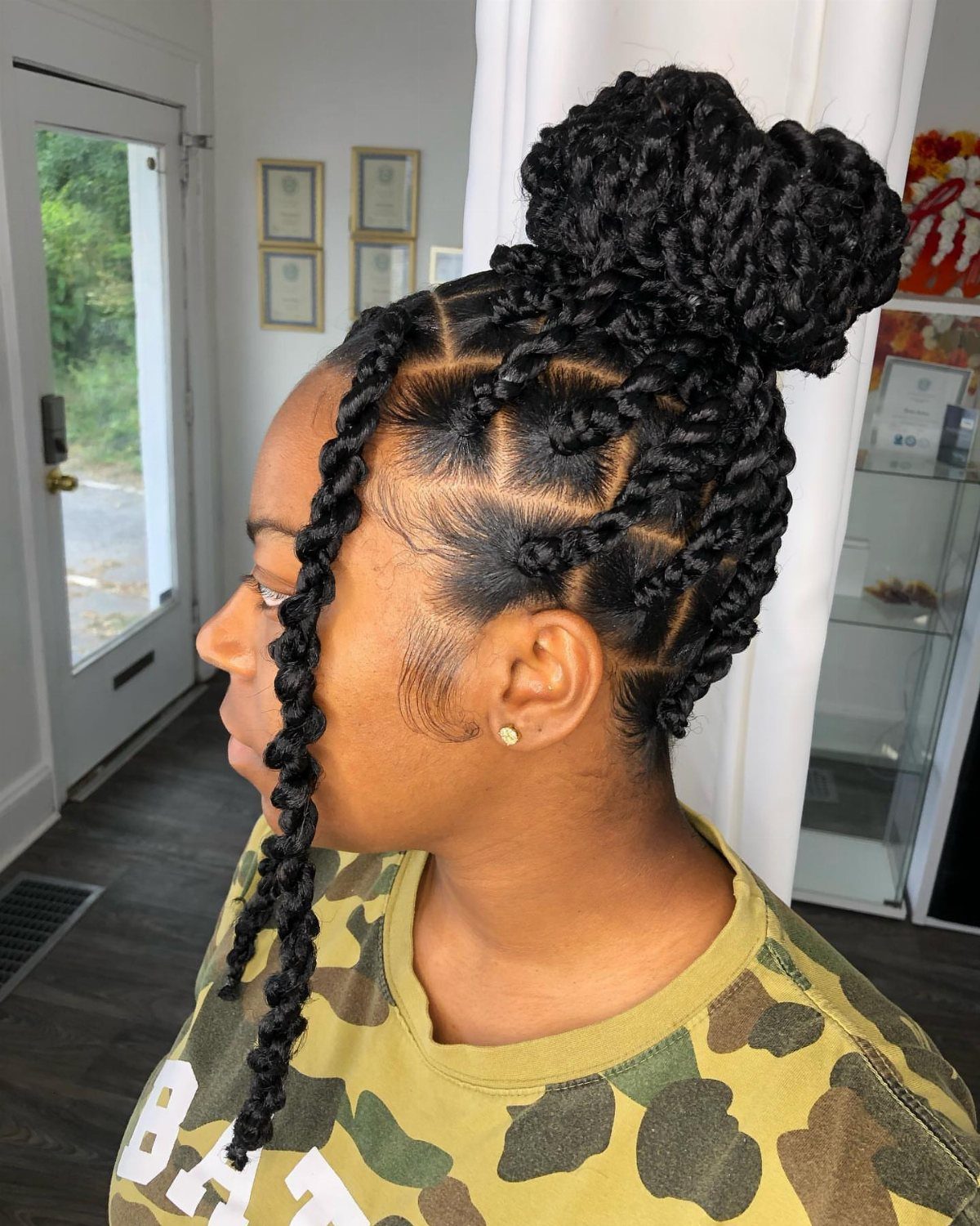 Black chunky twists gathered into a high bun with several twists hanging loose