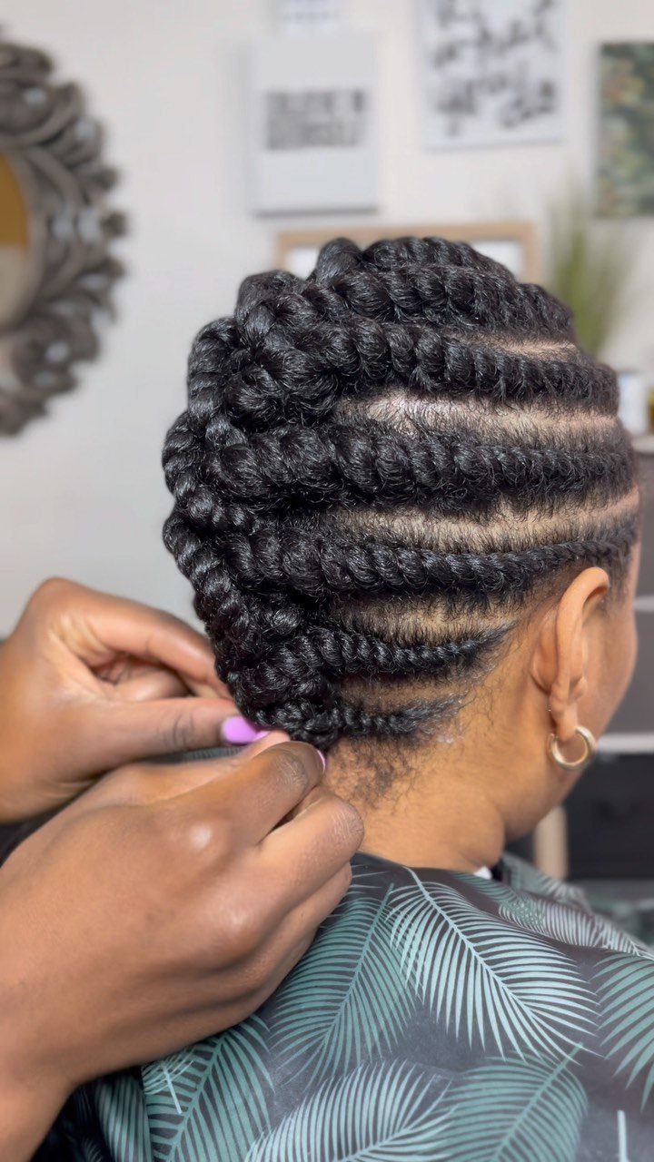 Thick black flat twists curve across the scalp and gather at the nape