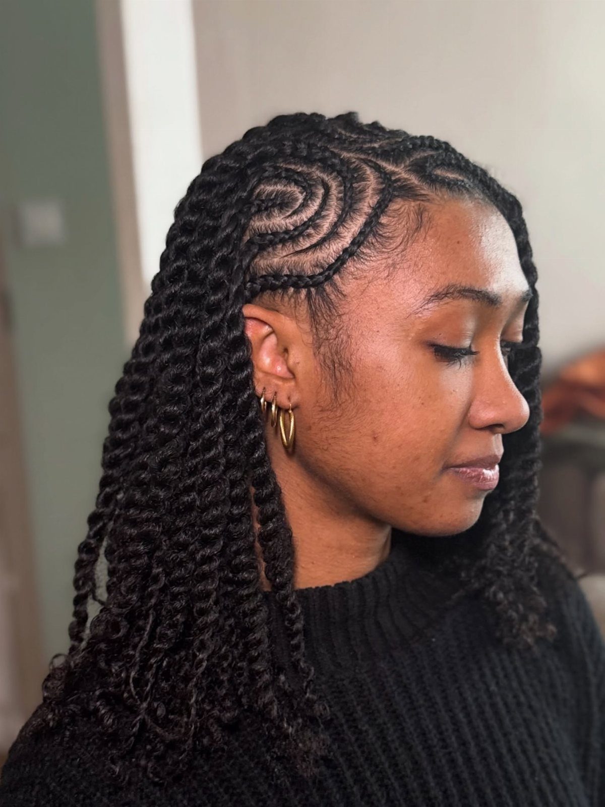 Woman with thick black twists swept over one shoulder and curved scalp braids