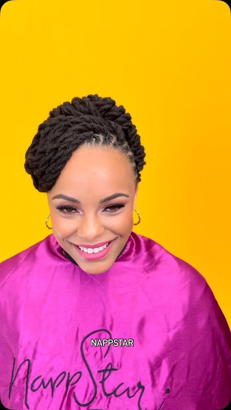 Woman smiling with thick natural twists gathered into a high updo