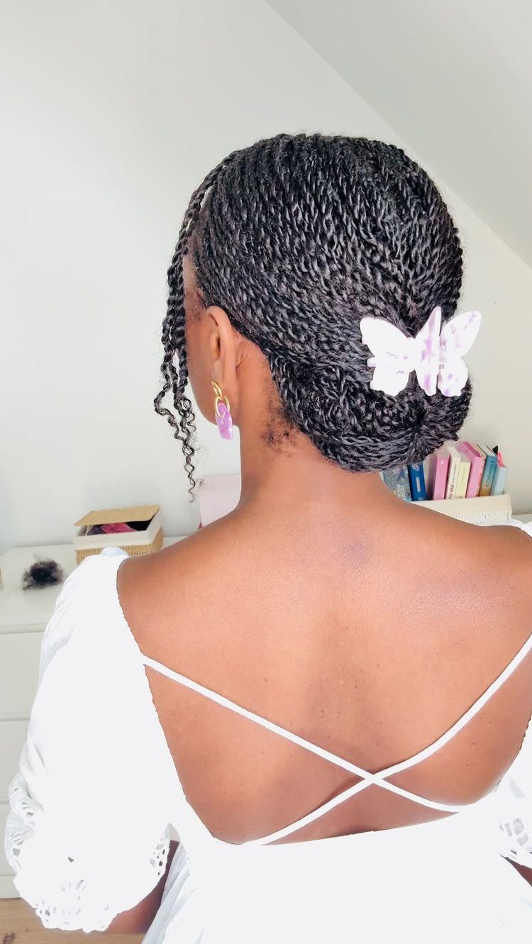 Natural twists gathered into a low bun with a pale butterfly clip