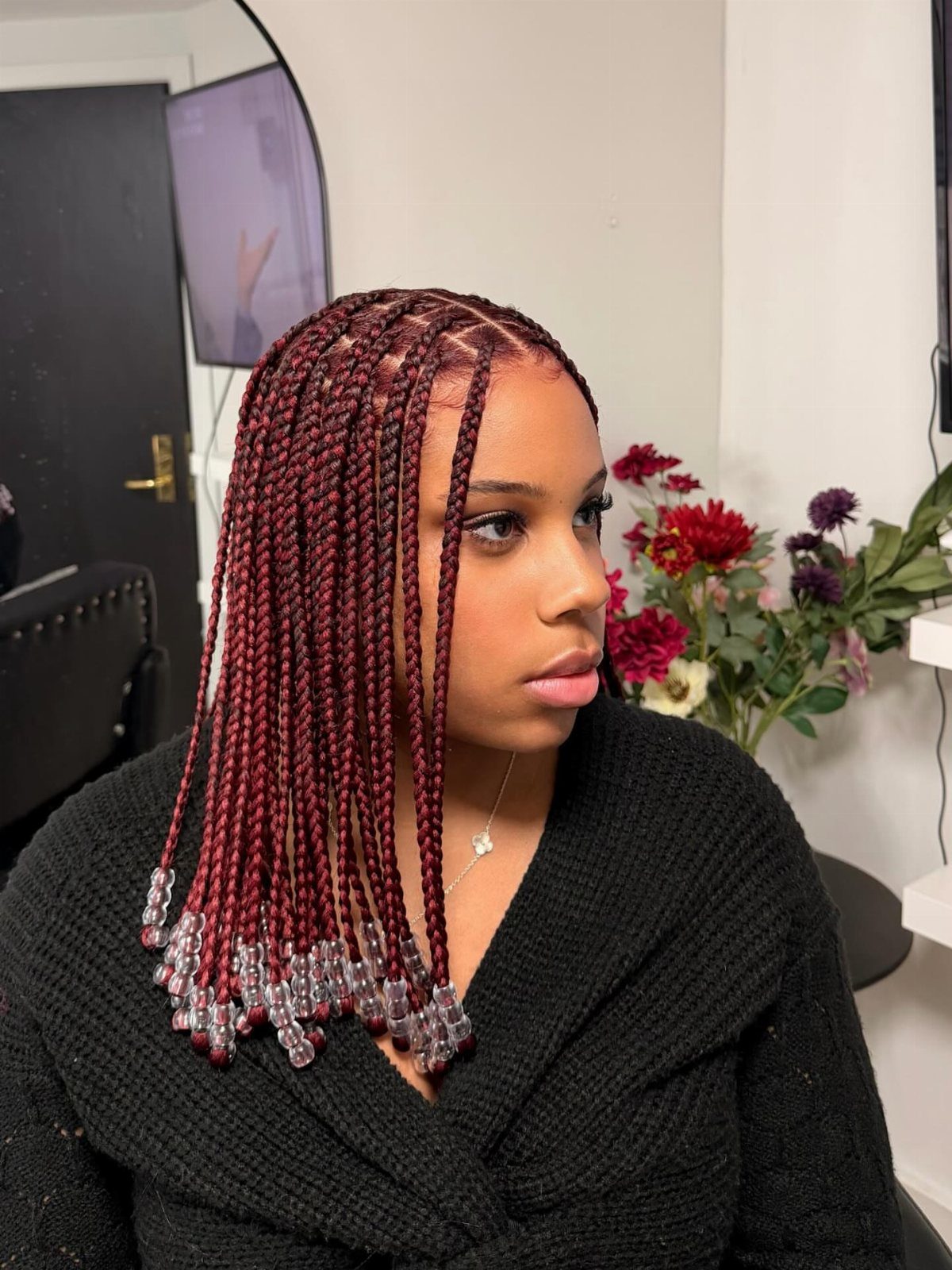 Woman wears burgundy box braids with clear beads at the ends