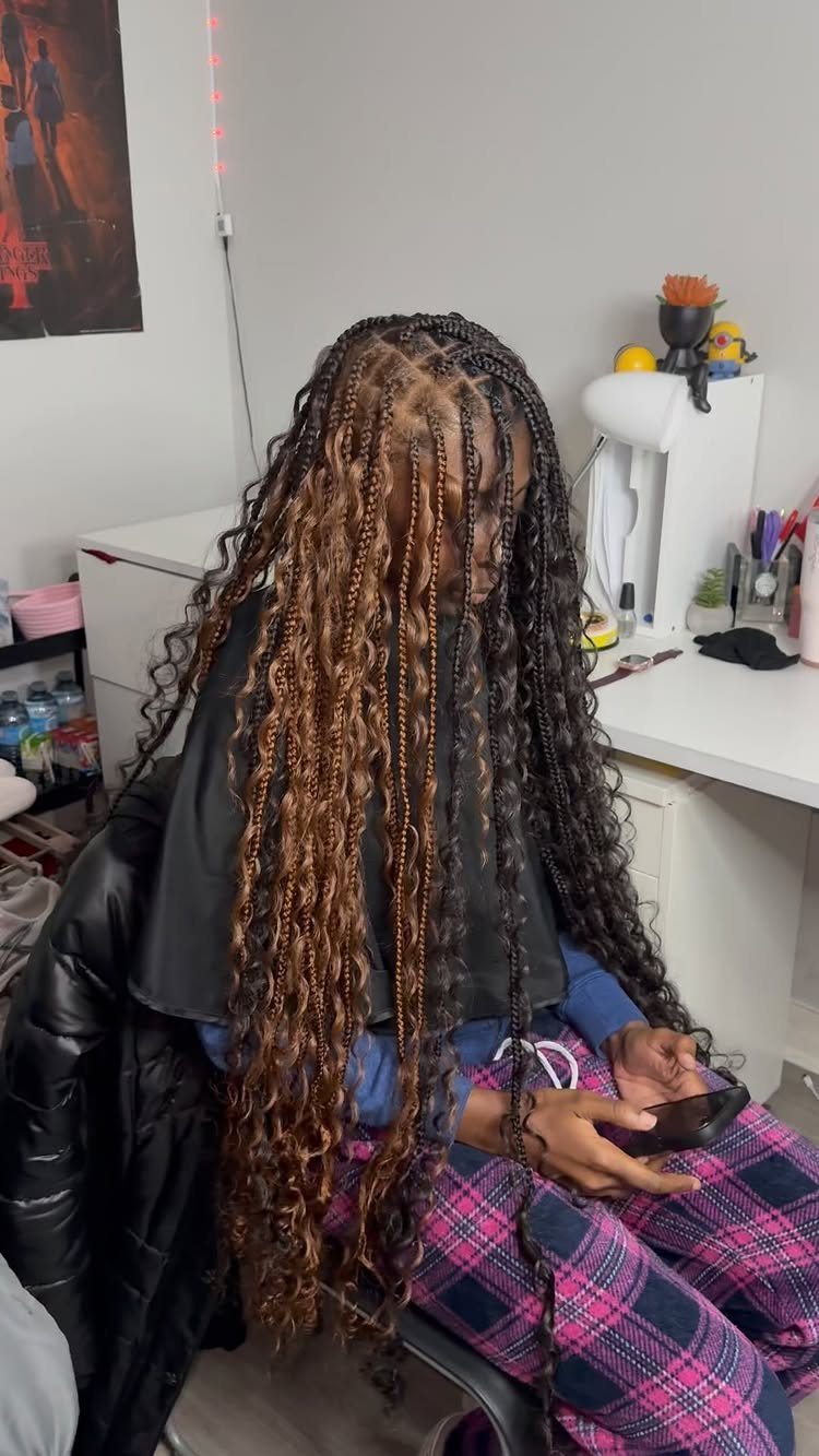 Long jumbo box braids cascading down a seated person's back in a salon