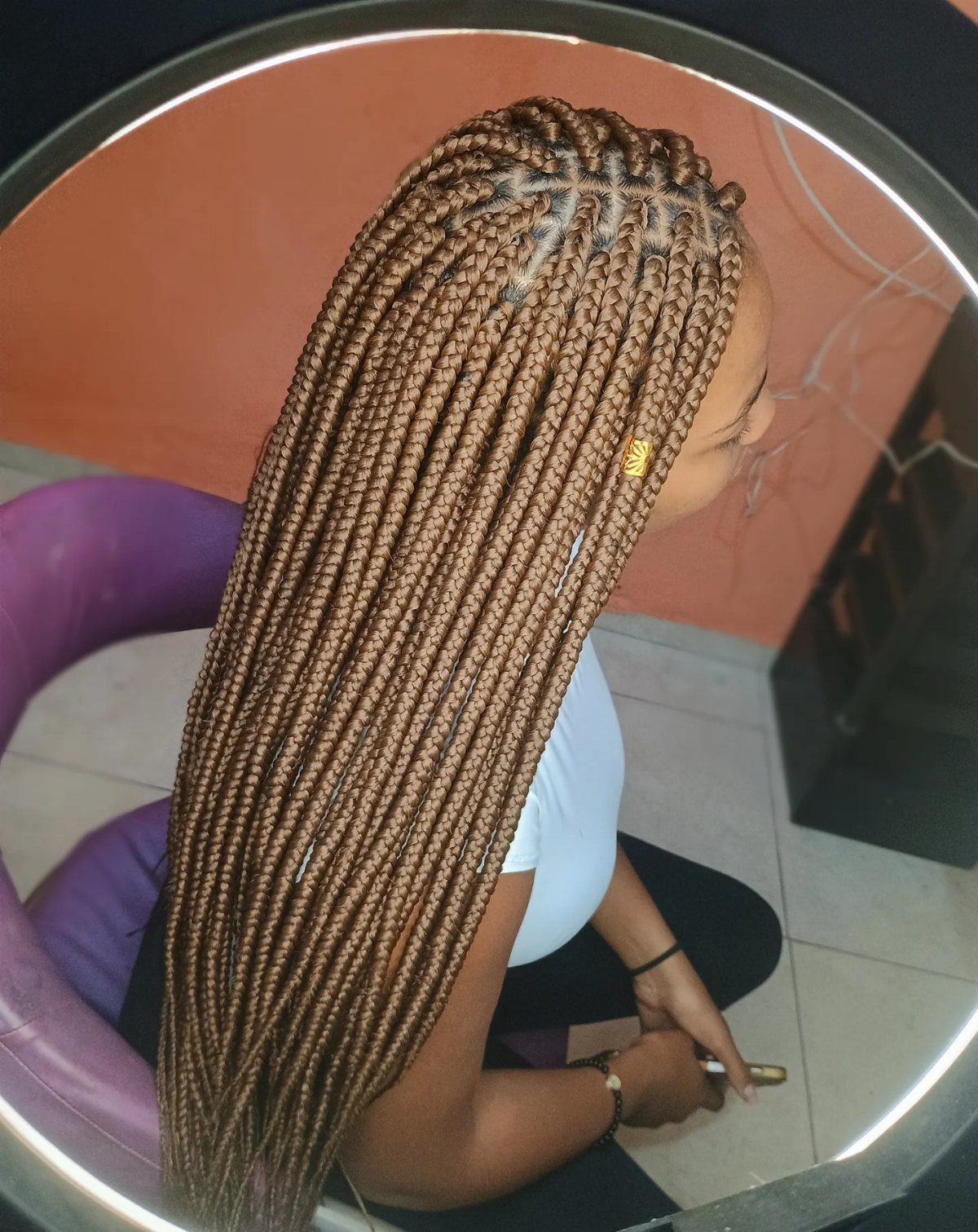 Long light-brown jumbo box braids with neat parts and a gold cuff