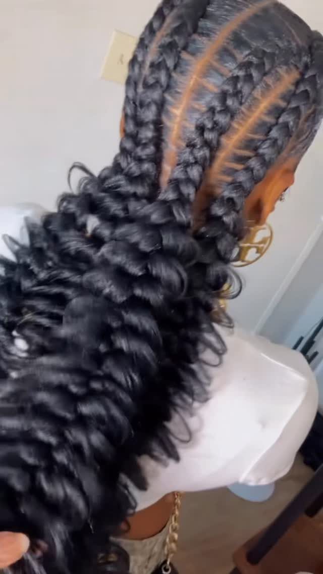Long black jumbo box braids gathered into a voluminous curly ponytail