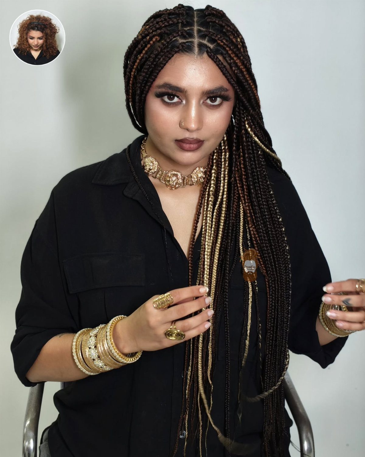 Woman wearing long dark box braids with gold strands and gold jewelry