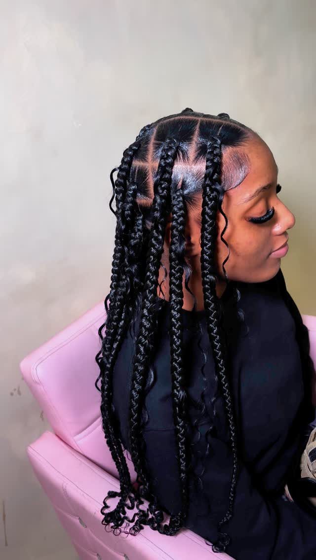 Woman with long jumbo box braids and loose curls seated in profile