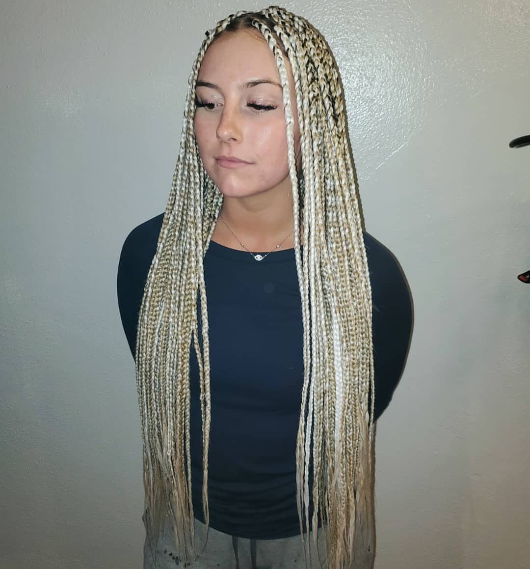 Woman displaying long, thick light blonde braids over a dark top