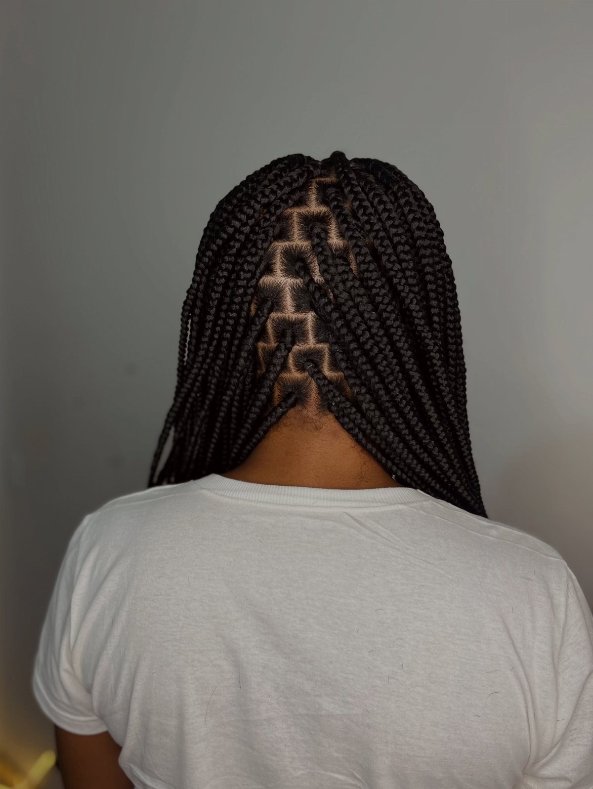Thick black box braids with geometric triangle parting shown from behind
