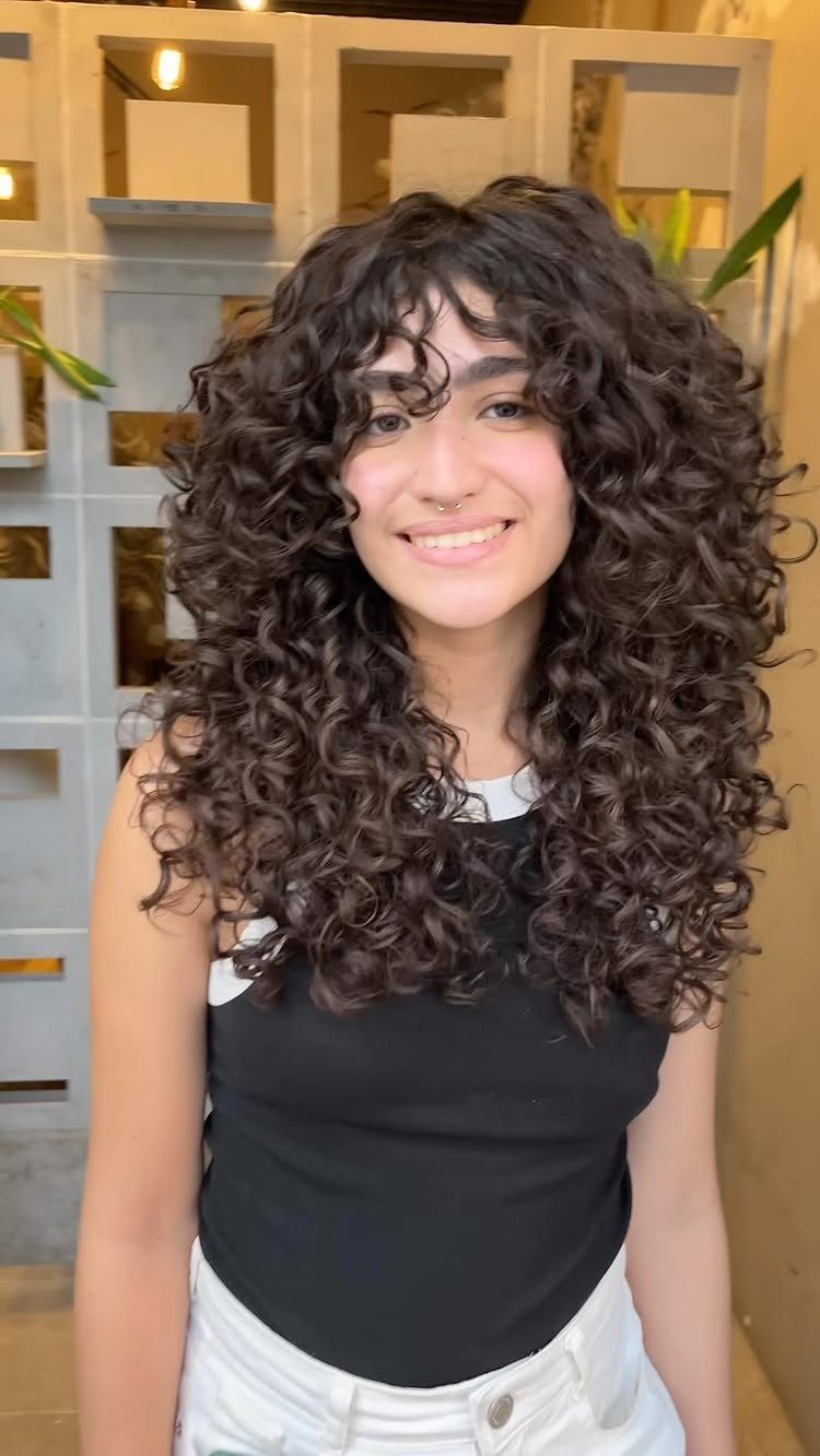 Young woman showing long, voluminous dark curls with layered lengths