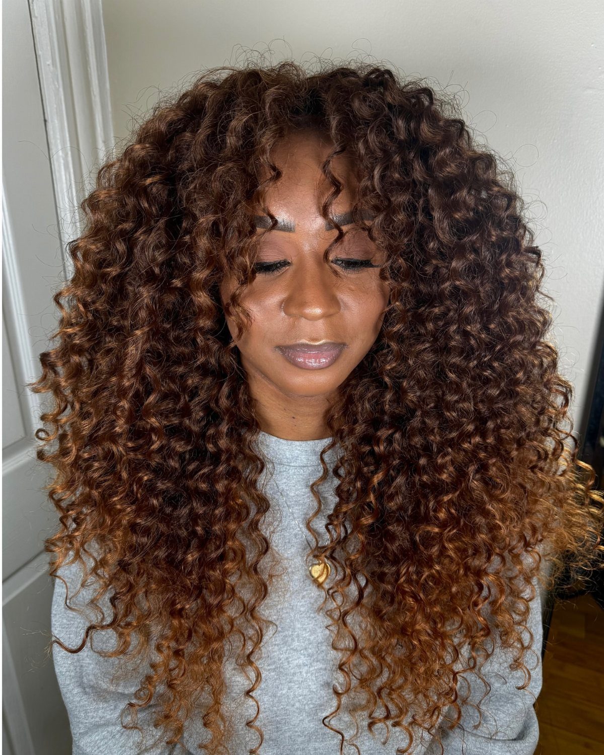 Woman with voluminous layered curls fading from dark brown to lighter brown ends