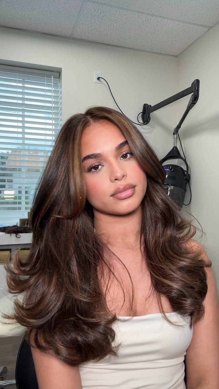 Woman with long layered brown hair styled in voluminous loose curls