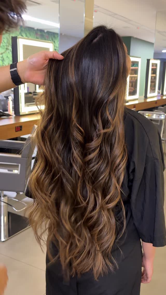 Long dark curls with graduated lighter brown balayage ends in a salon