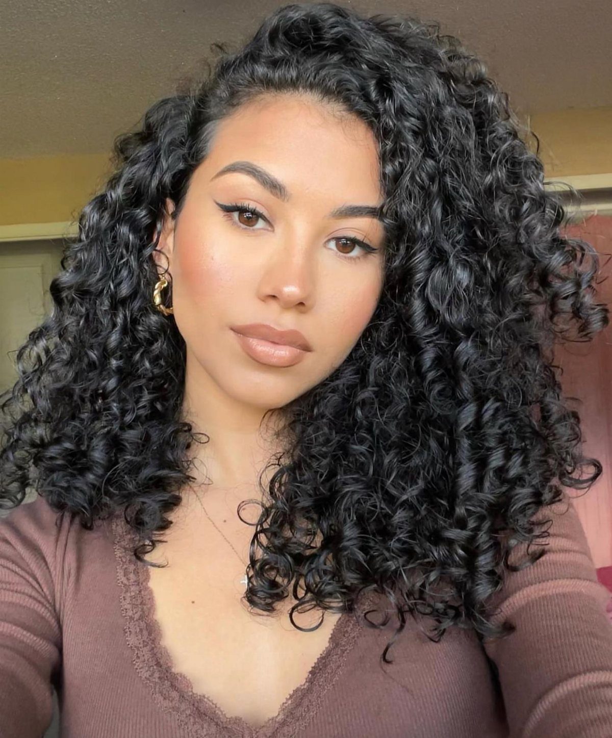 Woman with long, voluminous dark brunette curls framing her face