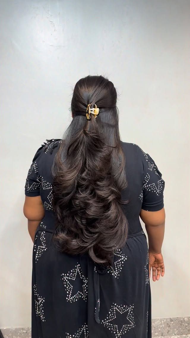Long dark layered curls fall down the back, partly held with a gold clip