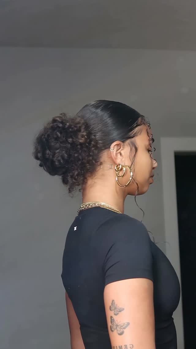 Woman with dark curls in a loose bun and face-framing tendrils