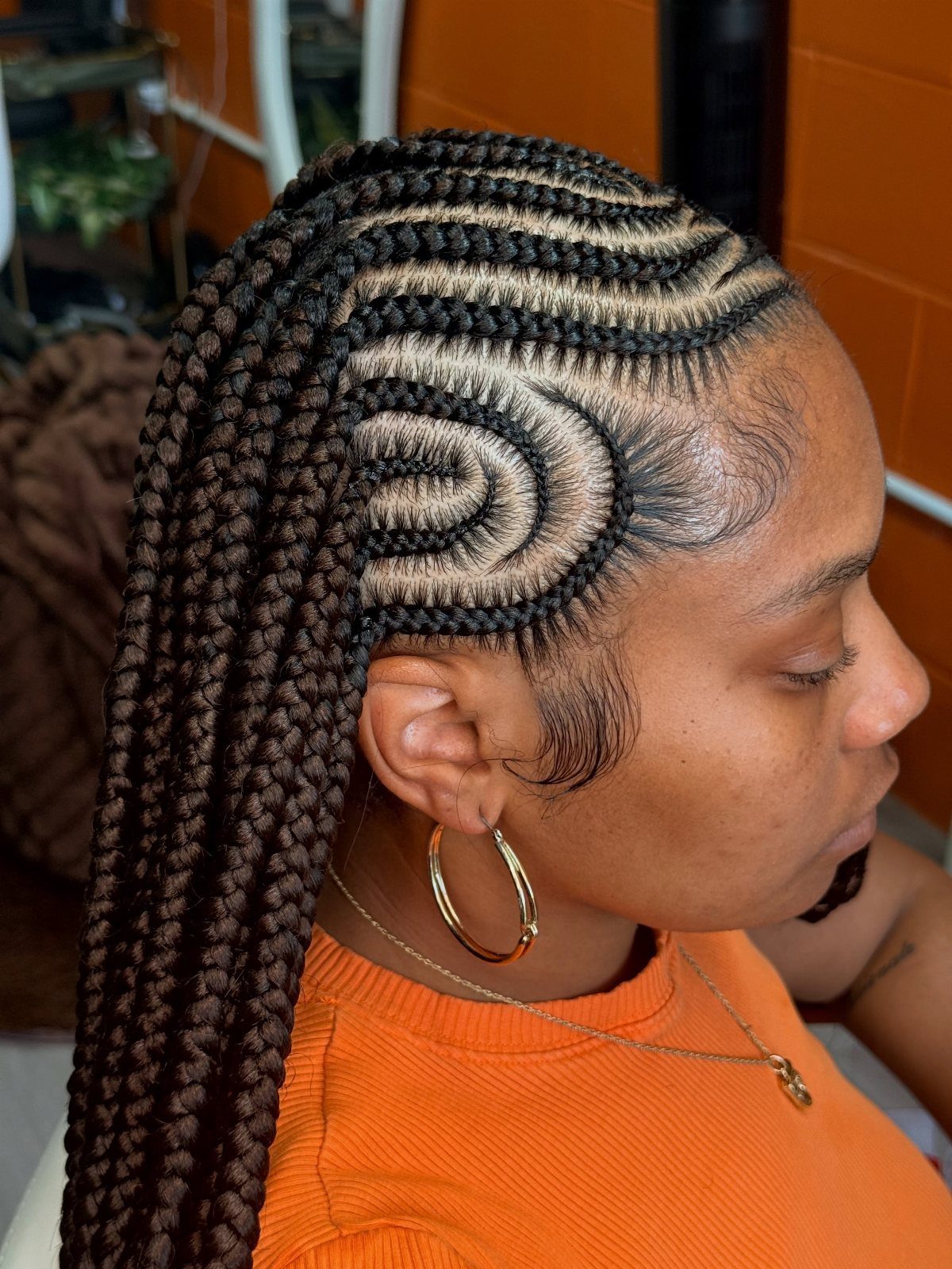 Woman with dark box braids and curved cornrows along the side of her head